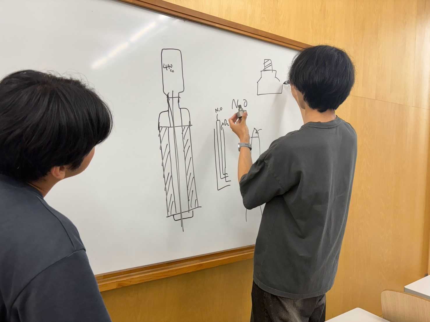 ホワイトボードでハイブリッドエンジンの構成を検討するメンバー